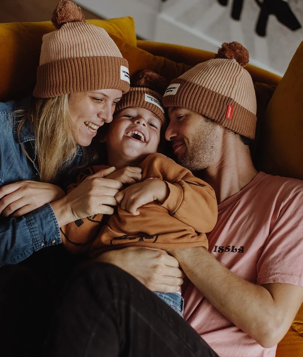 Parents et leur enfant en bonnets, blottis sur un canapé