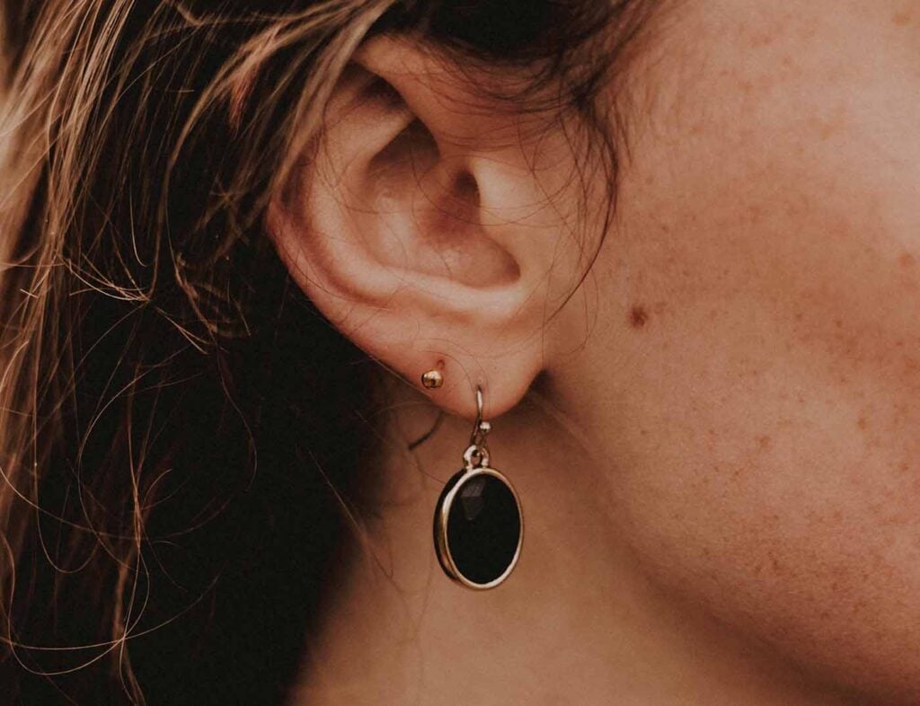 femme avec boucle d'oreille pendentif pierre noire