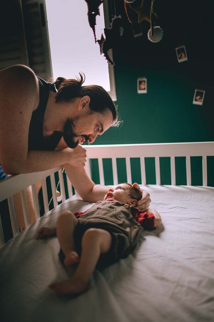 papa caresse son bébé couché dans son lit