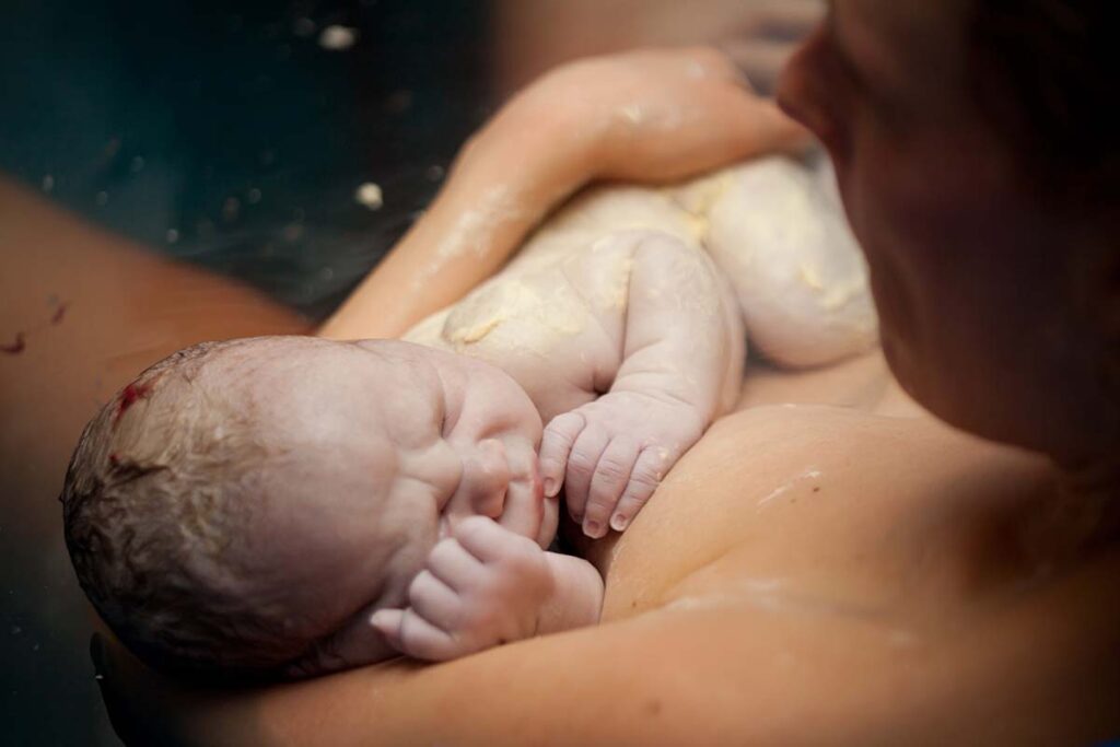 accouchement naturel dans l'eau avec bébé qui vient de naître contre sa maman en peau à peau
