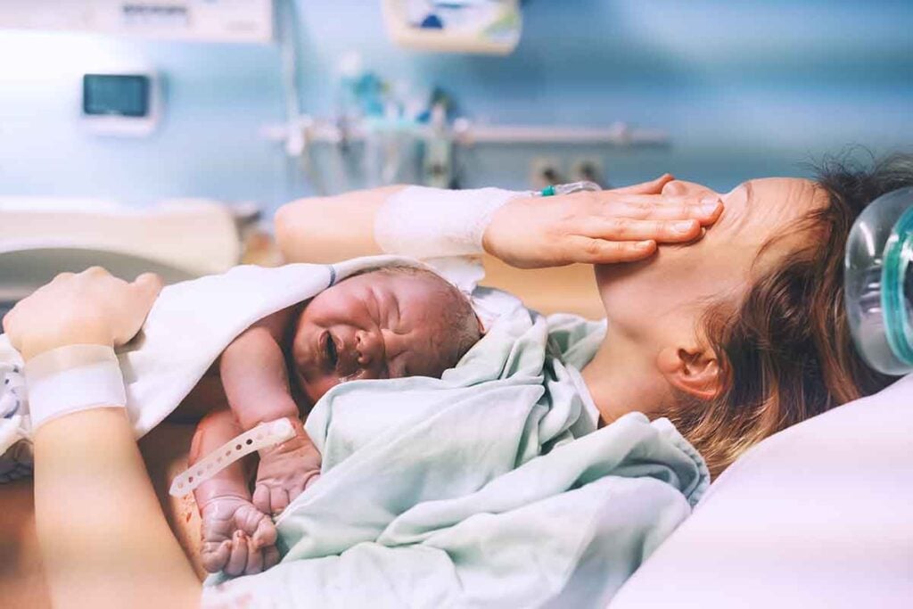 nouvelle maman pleure d'émotion avec son bébé dans les bras suite d'accouchement