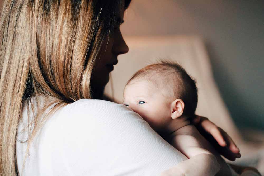 maman en post partum porte en peau à peau son bébé