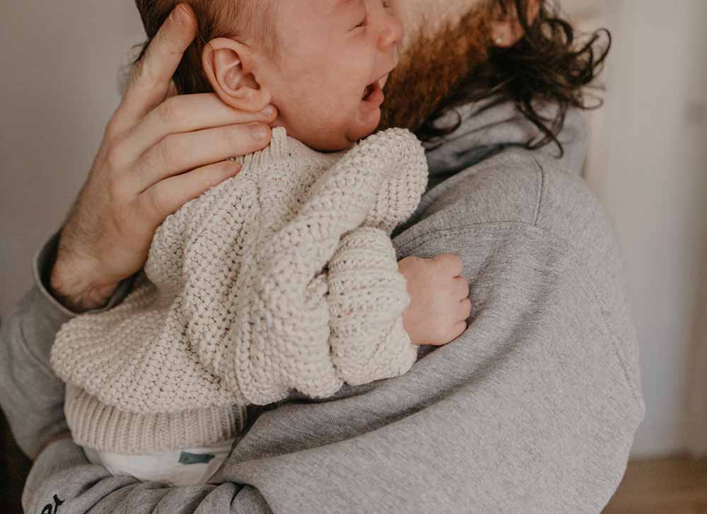 papa tient son bébé qui pleure stress dû à la séparation avec solutions pour calmer le stress parental