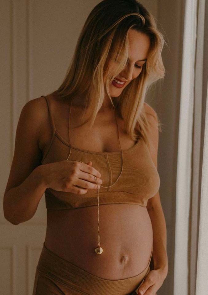 Bola de grossesse élégamment suspendu au-dessus d'un ventre arrondi de femme enceinte.