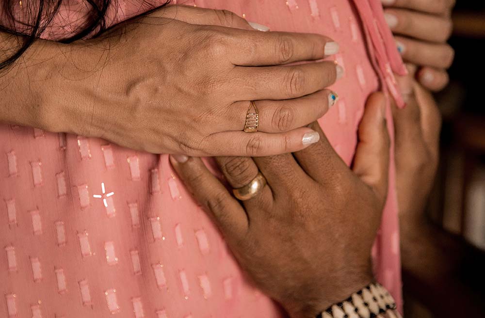 Tendresse qui symbolise le "lien d'attachement bébé grossesse". On y voit les mains d'une femme enceinte et celles d'une autre personne, peut-être le partenaire, délicatement posées sur son ventre arrondi. Les mains expriment douceur et protection, suggérant un geste de connexion et d'anticipation avec l'enfant à naître. Cette photographie intime évoque l'importance du contact et de l'affection dans le développement d'un lien précoce entre les parents et leur bébé, même avant la naissance.