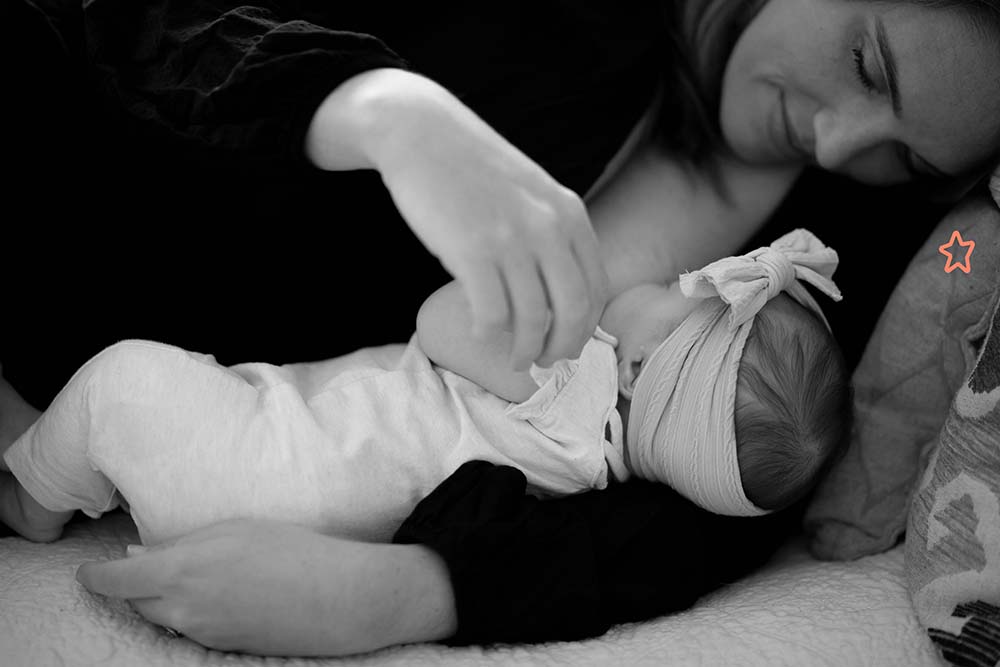 Une mère allaitant tendrement son bébé la nuit avec le soutien du papa, mettant en lumière l'importance de la présence et de l'assistance paternelle pendant les tétées nocturnes pour le confort et le bien-être de la mère et de l'enfant.