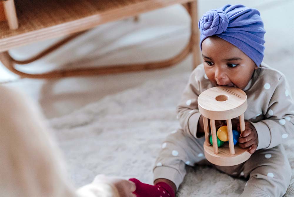 Éveil et jeu : un bébé adopté découvre un nouveau jouet, symbolisant les premières interactions et l'apprentissage dans un environnement familial aimant suite à l'adoption. Bien accueillir un enfant adopté.