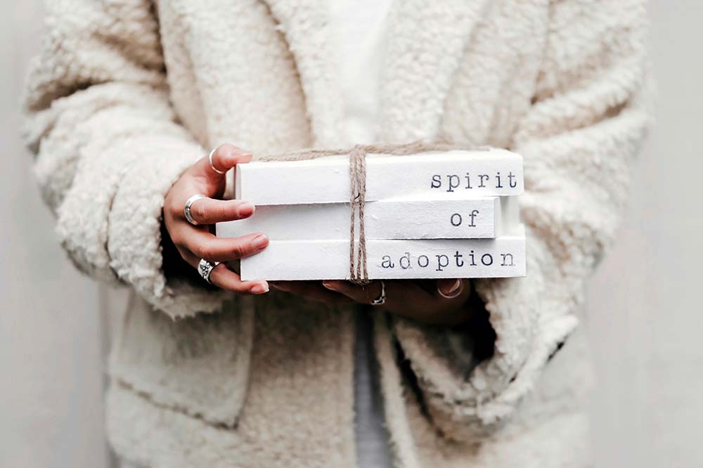Célébrer l'adoption : une personne tenant des livres intitulés 'spirit of adoption', symbolisant le soutien et la préparation des familles dans le processus d'accueil d'un bébé adopté.
