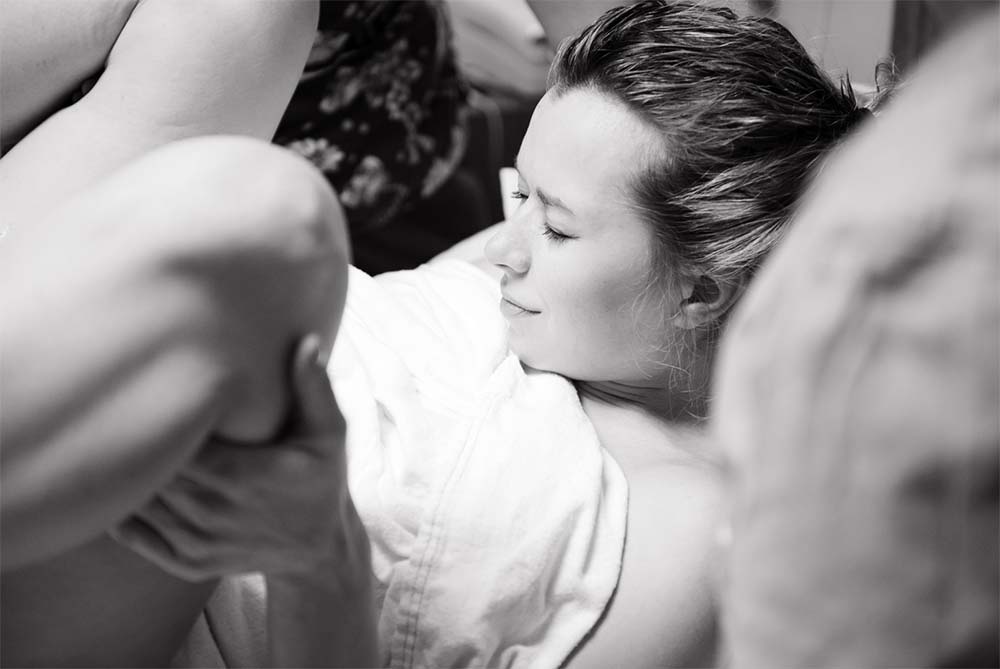 Soutien et confort pendant l'accouchement : une femme en travail trouve du réconfort dans une position d'accouchement allongée assistée, entourée par une équipe de soutien attentive.