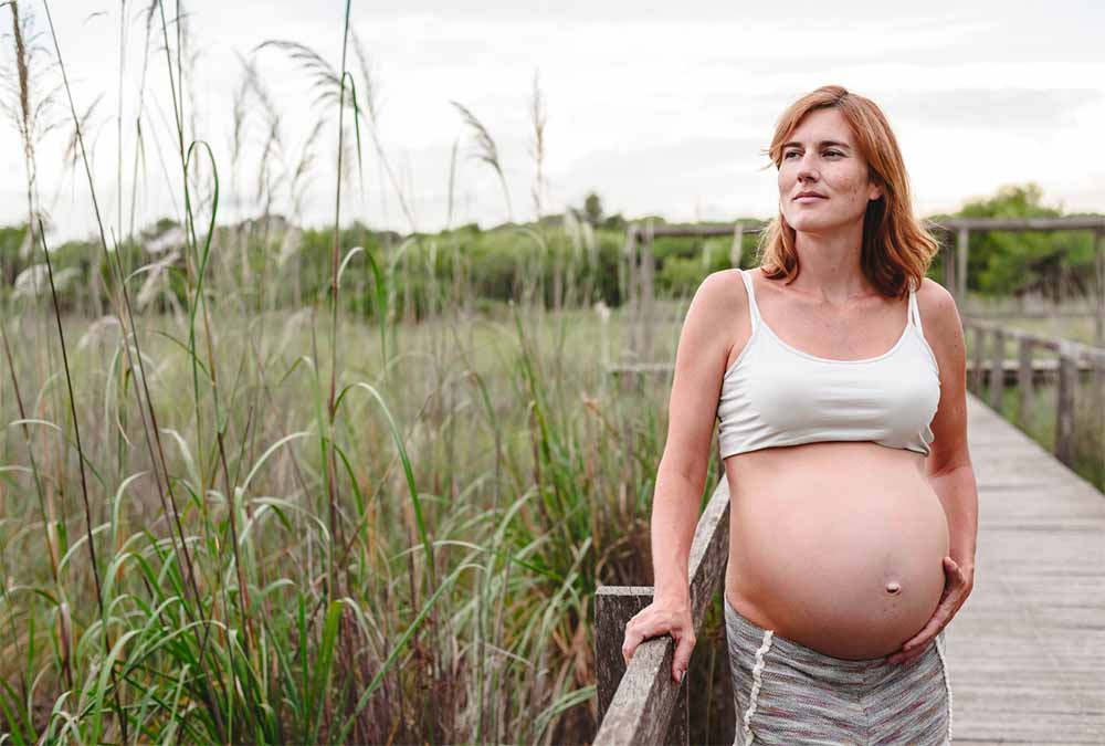 Conseils pour préparer et accélérer le travail naturellement en fin de grossesse, illustrés par une future maman en plein air, intégrant activité physique adaptée et relaxation.