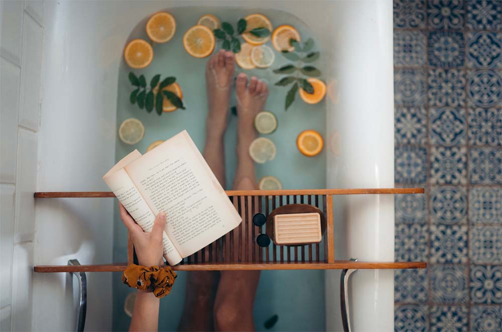 Détente et relaxation à domicile : une femme enceinte profite d'un bain parfumé aux agrumes et lit un livre, tout en restant à l'écoute de son corps pour les signes d'un accouchement imminent.