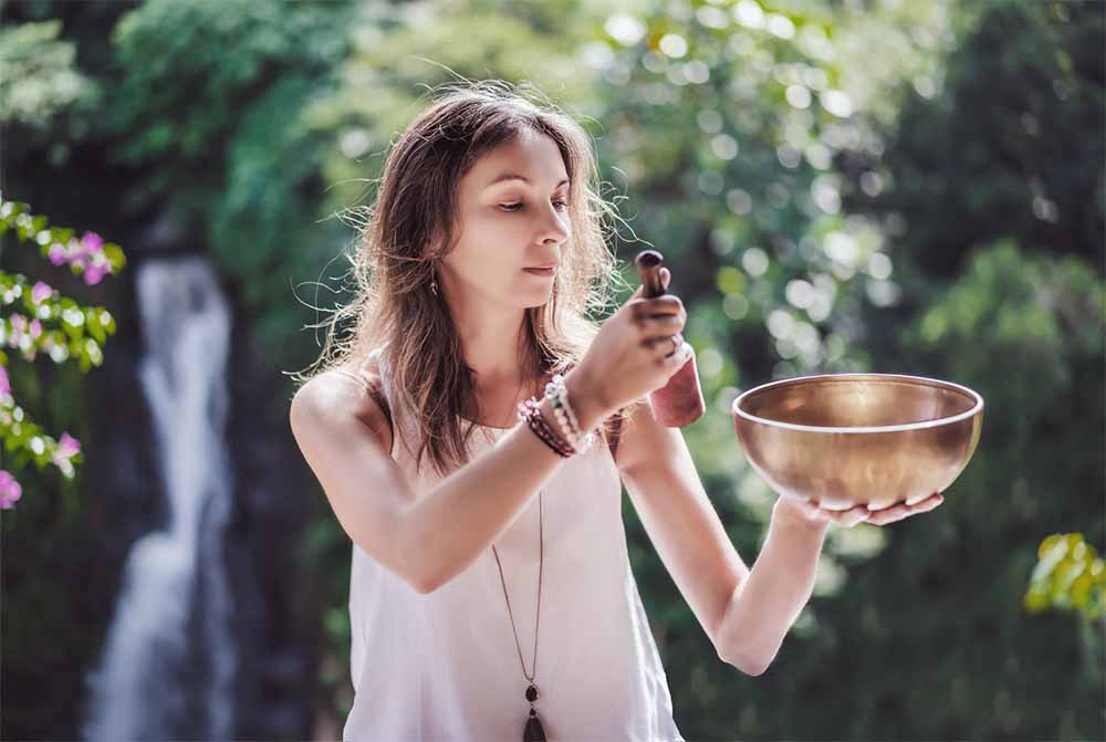 Femme enceinte utilisant un bol chantant pour la relaxation et la concentration, intégrant les techniques de chant prénatal pour un accouchement physiologique harmonieux.