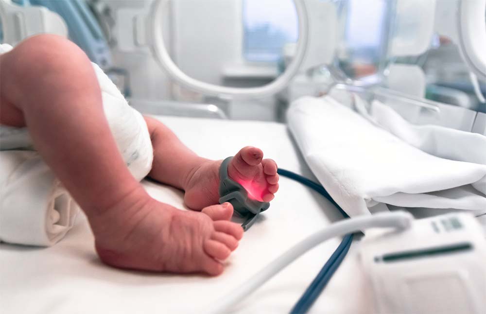 Petits pieds d'un bébé prématuré recevant des soins médicaux spécialisés dans une unité de néonatalogie, illustrant l'importance de l'assistance et de la surveillance continue pour les nouveau-nés arrivant avant terme.