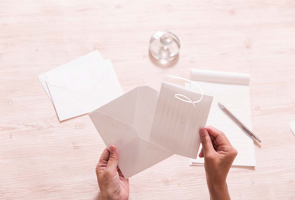 Modèles de lettres et cartes pour féliciter la naissance d'un bébé, avec enveloppes et stylo sur une table en bois. Idées de textes de félicitations pour nouveau-né, exemples de vœux de bienvenue pour enfant, phrases pour cartes de naissance, suggestions de messages chaleureux pour parents et bébé, inspirations de lettres personnalisées pour célébrer un nouveau membre de la famille.