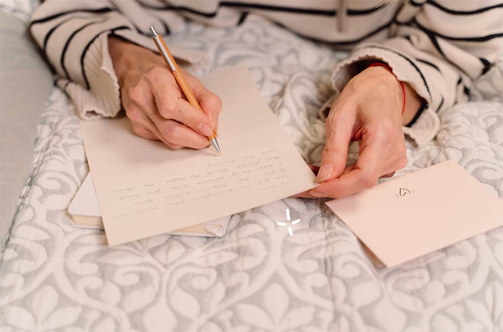 Idées et exemples de textes de félicitations pour la naissance à écrire à la main, montrant une personne en train de rédiger un message attentionné sur une carte de vœux, symbole de soin personnel et de tradition dans la communication des heureux événements.