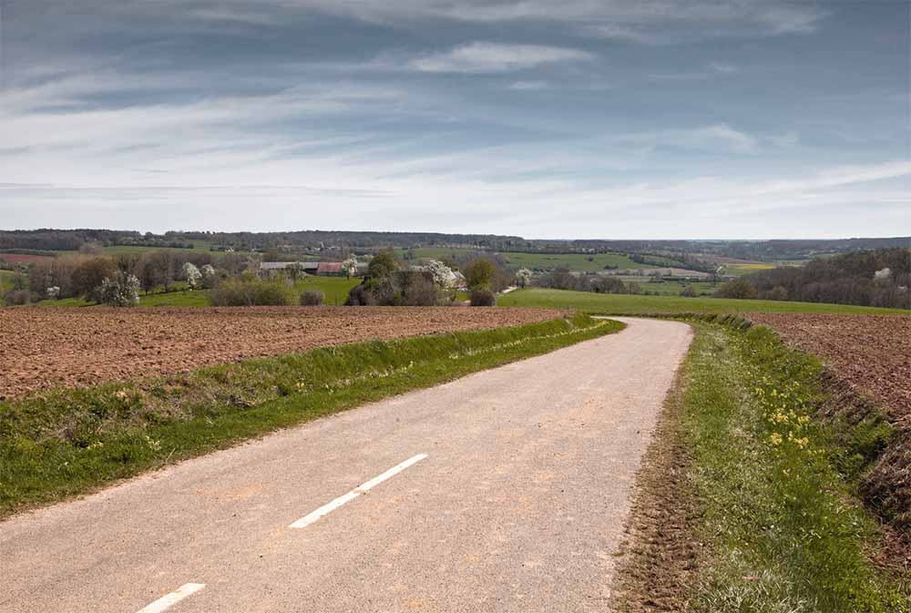 Rouler en voiture sur des chemins de campagne comme méthode naturelle pour provoquer le travail et favoriser le déclenchement de l'accouchement, illustré par une route rurale paisible propice à la promenade.