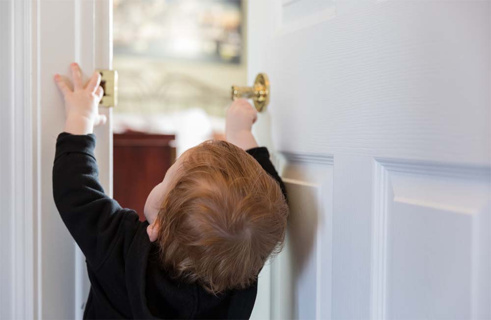 Bébé atteignant la poignée d'une porte : Sécurisez votre maison et protégez vos enfants avec nos conseils pour un foyer à l'épreuve des bébés. Solutions et astuces pour un environnement domestique sécuritaire pour les tout-petits.