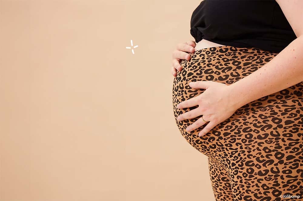 Zoom sur le ventre arrondi d'une femme enceinte portant un legging à imprimé léopard, un incontournable mode pour une grossesse stylée, confortable et moderne.