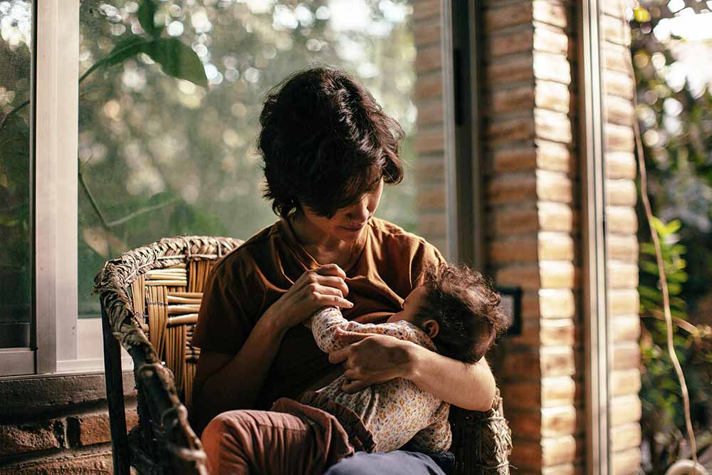 Mère allaitant son bébé en toute sérénité, exploration des choix d'allaitement, conseils sur l'alimentation au sein et alternatives avec lait infantile, débat et soutien à la parentalité.