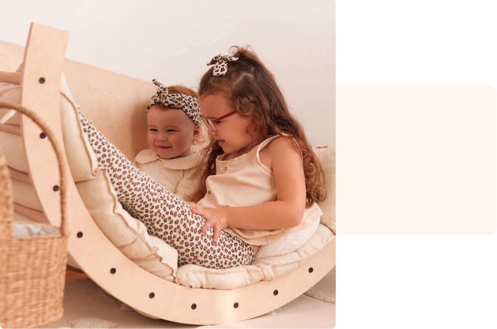 Deux petites sœurs complices dans leur balancelle en bois, témoignage fratrie