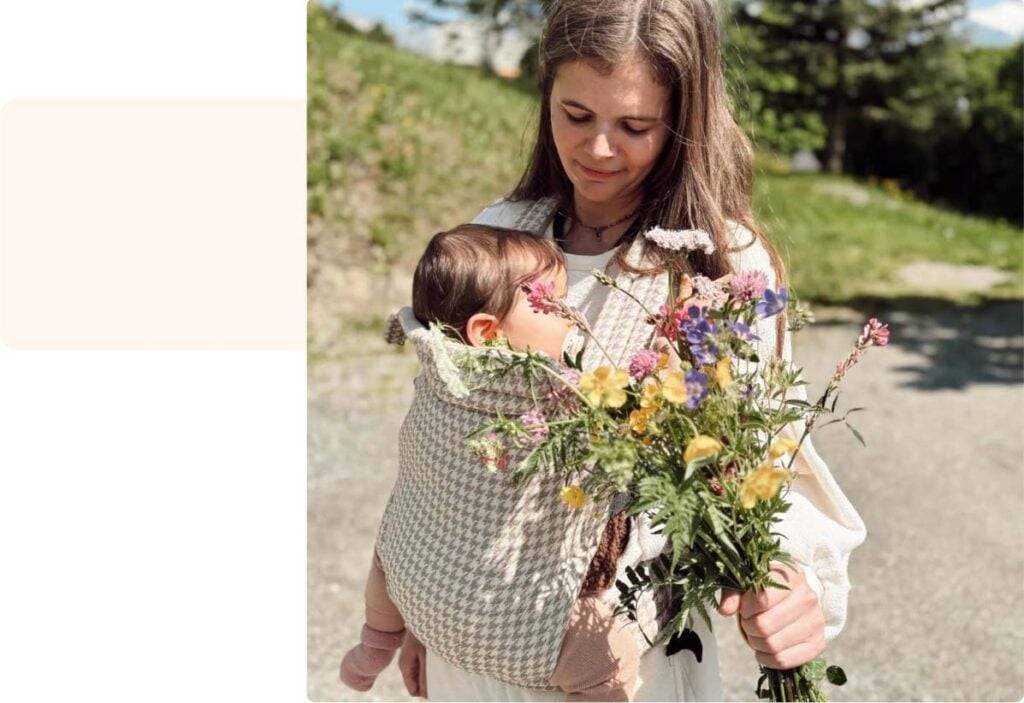 Maman portant son bébé endormi dans une écharpe de portage, témoignage maman sur la simplicité et la nature