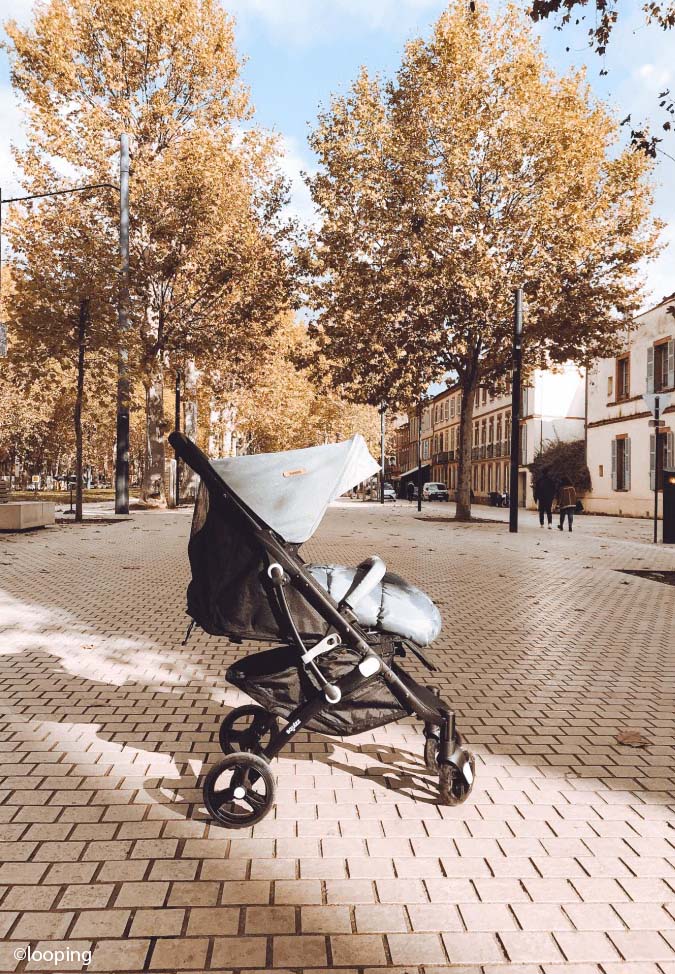 Poussette avec un bébé allongé lors d’une promenade automnale en ville, activité bébé 0-3 mois idéale pour découvrir de nouveaux sons et lumières