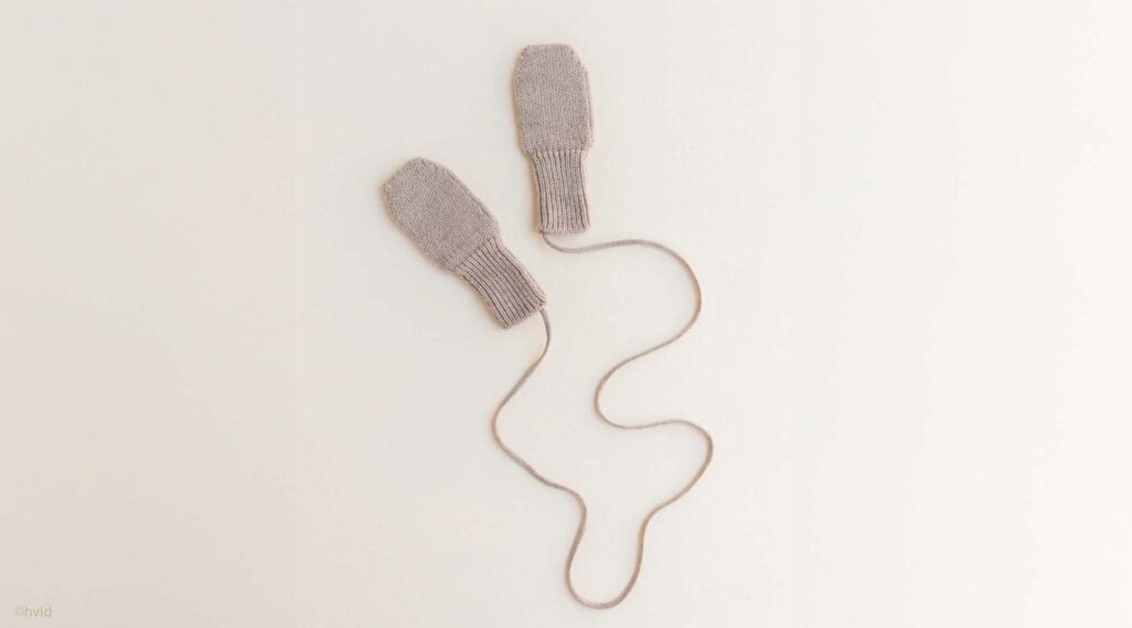 Petites moufles en laine reliées par un cordon, accessoire doux et pratique pour protéger bébé du froid