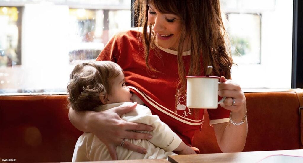 Femme allaitant son enfant sur une banquette de café, geste naturel d'allaiter en public