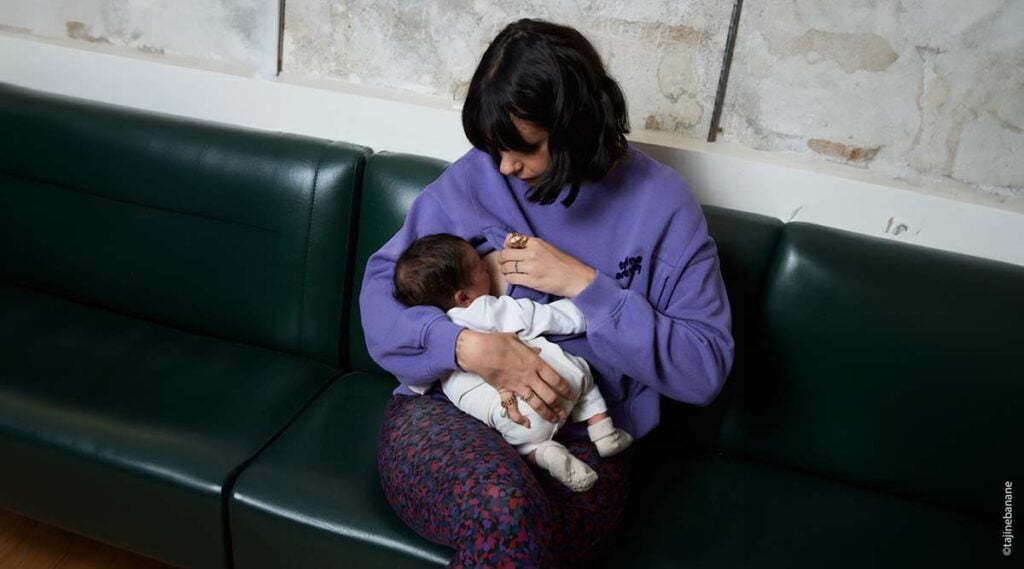 femme enceinte en t-shirt lilas ajustant un accessoire d'allaitement en extérieur, préparation à l'allaitement maternel