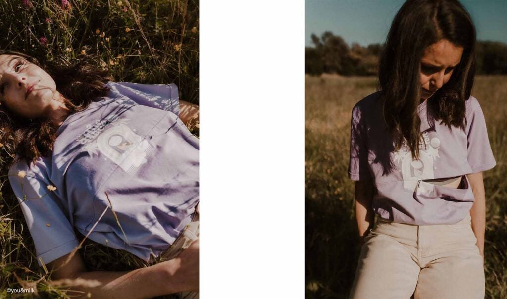 ère allongée dans un champ fleuri portant un t-shirt lilas, célébrant la maternité en pleine nature