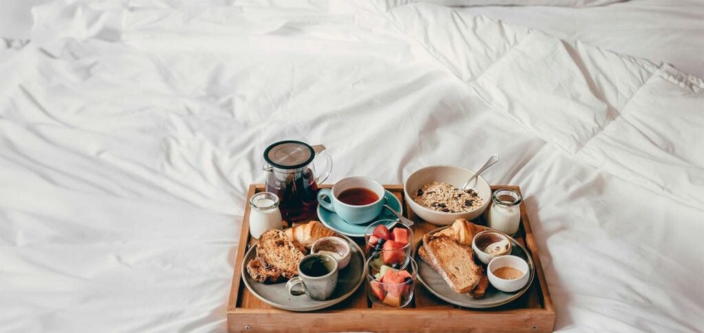 Plateau de petit-déjeuner en couple au lit avec croissants et fruits frais avant l'arrivée de bébé
