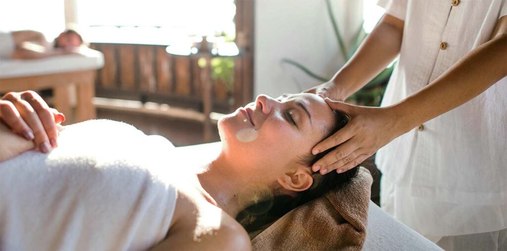 Femme enceinte recevant un massage facial relaxant à partager en couple dans un spa avant l'arrivée de bébé