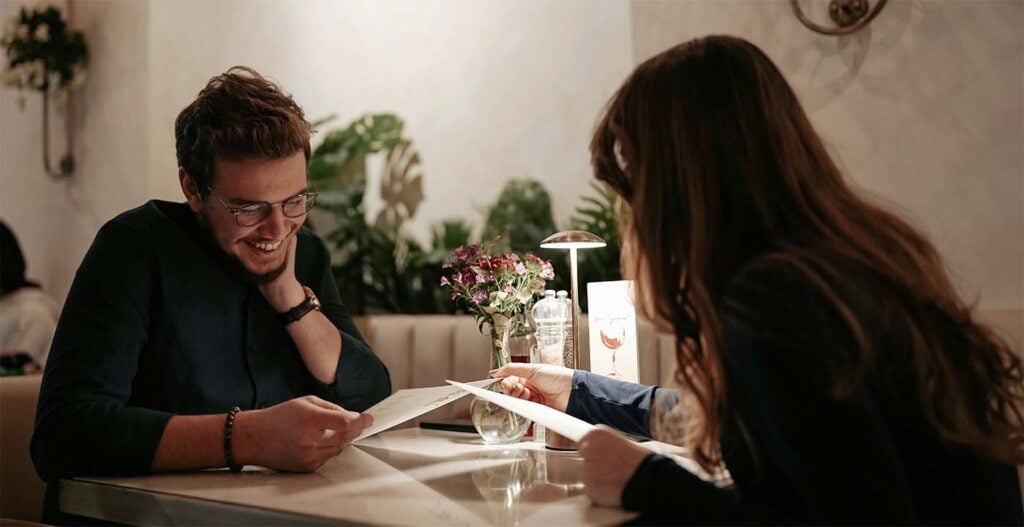 Couple partageant un dîner aux chandelles dans un restaurant intimiste avant l'arrivée de bébé, activité à faire en couple