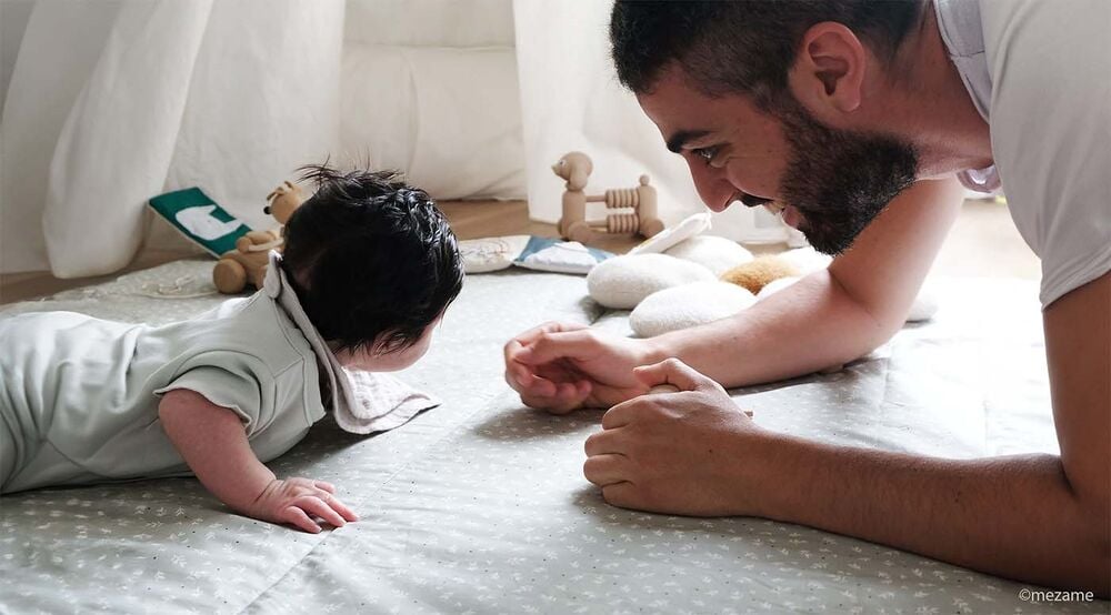 Séance de tummy time bébé au sol avec parent, exercice motricité pour renforcer nuque et dos