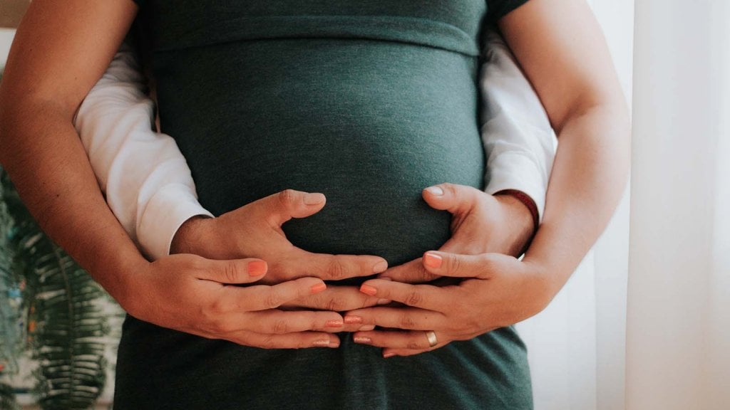 femme enceinte avec les mains posées sur le ventre du papa et de la maman