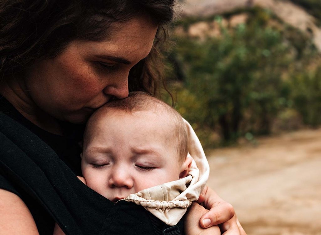 Mère étreignant tendrement son bébé en pleine nature, illustrant l'importance de reconnaître et de différencier la dépression post-partum du burn-out parental maternel.