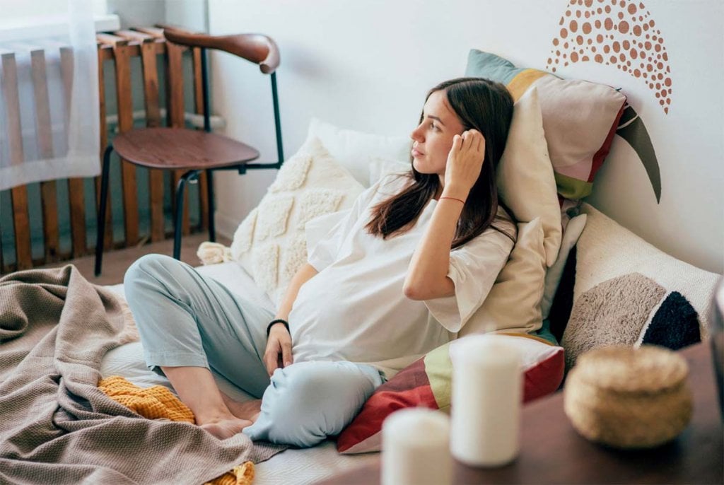 Femme enceinte se reposant paisiblement à la maison, se préparant mentalement à un accouchement physiologique grâce à des techniques de relaxation et de visualisation positive.