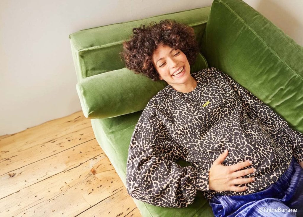 Future maman rayonnante et détendue dans un sweat à motif léopard Tajine Banane, exemple tendance de tenue de maternité confortable pour rester stylée pendant la grossesse.