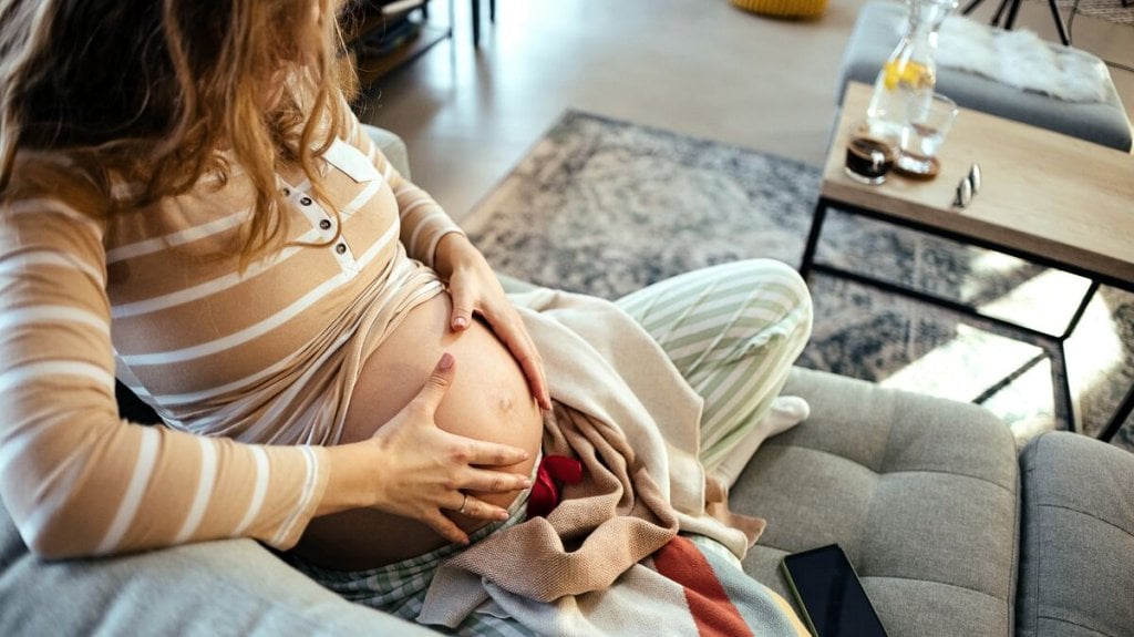 Femme enceinte en fin de grossesse ressentant des contractions de Braxton Hicks à la maison