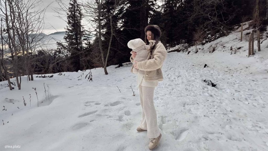 Maman emmitouflée tenant son bébé contre elle dans la neige, moment tendre pour protéger bébé du froid en hiver