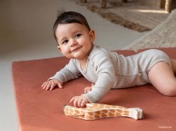 Bébé souriant prêt pour l'apprentissage avec son jouet, illustrant l'importance de bien choisir et déclarer assistante maternelle. Guide complet pour embaucher une nounou.