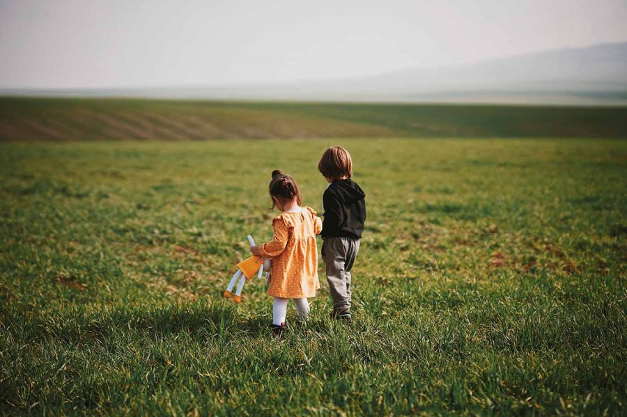 un frère et sa petite soeur avec robre jaune dans un champ